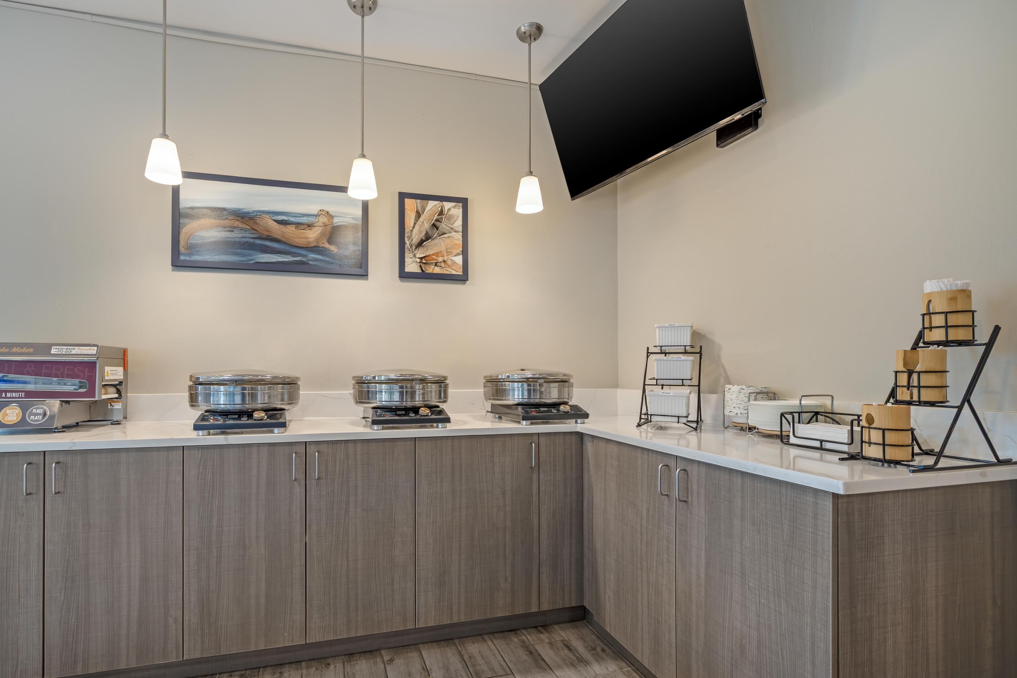 A modern kitchen with built-in appliances, pendant lighting, and artwork on the wall.