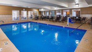 A swimming pool with a tiled edge, surrounded by lounge chairs and tables, and a clock on the wall. - Best Western Plus Pioneer Park Inn (Fairbanks)