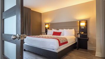 A neatly made bed with a white and red bedspread, two bedside lamps, and a dark wooden nightstand.