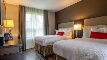 Een hotelkamer met twee bedden, een bureau en een stoel.