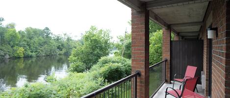 A balcony with a view of a river and surrounding greenery.