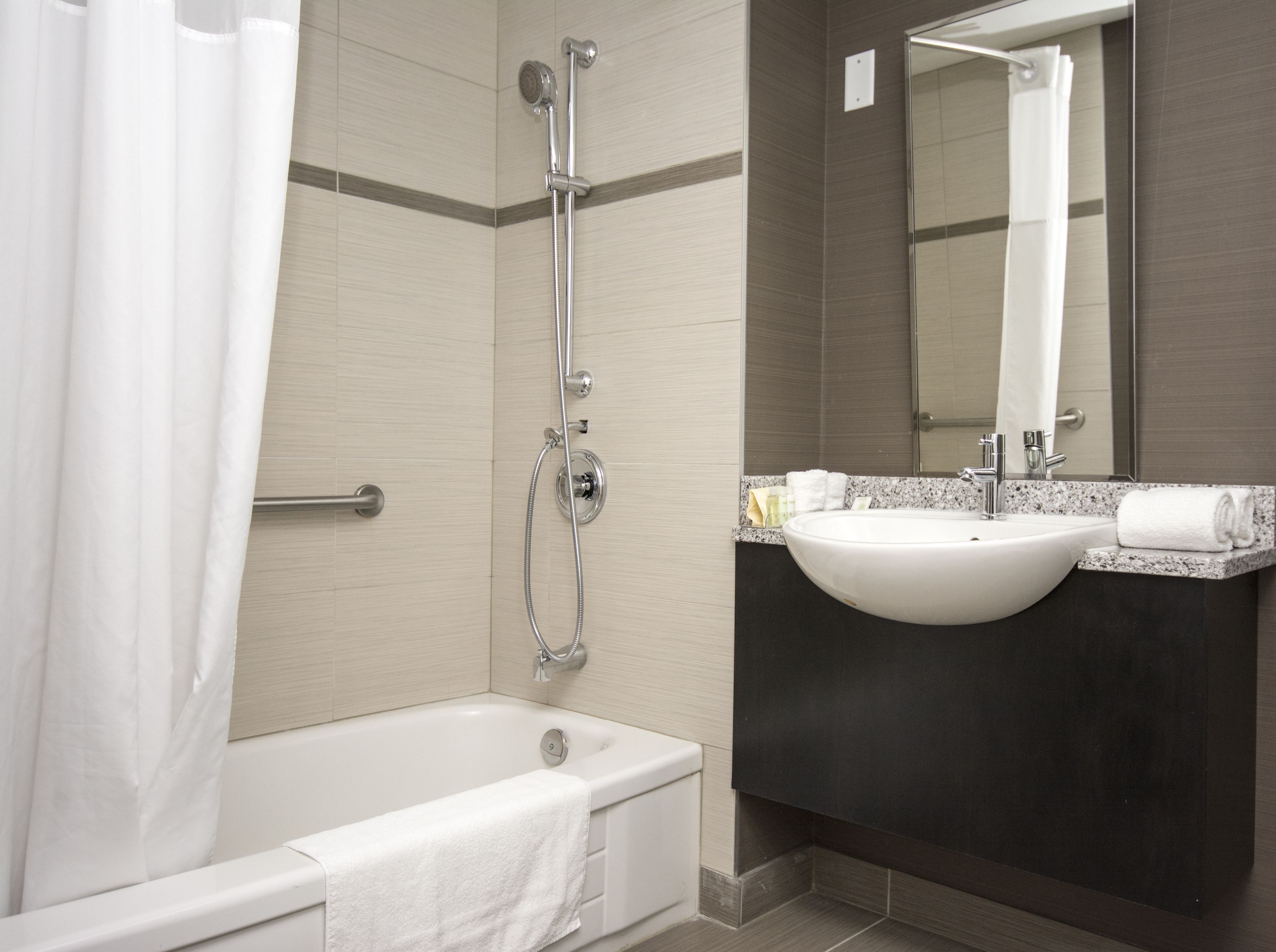 Een moderne badkamer met een bad, douche en wastafel.