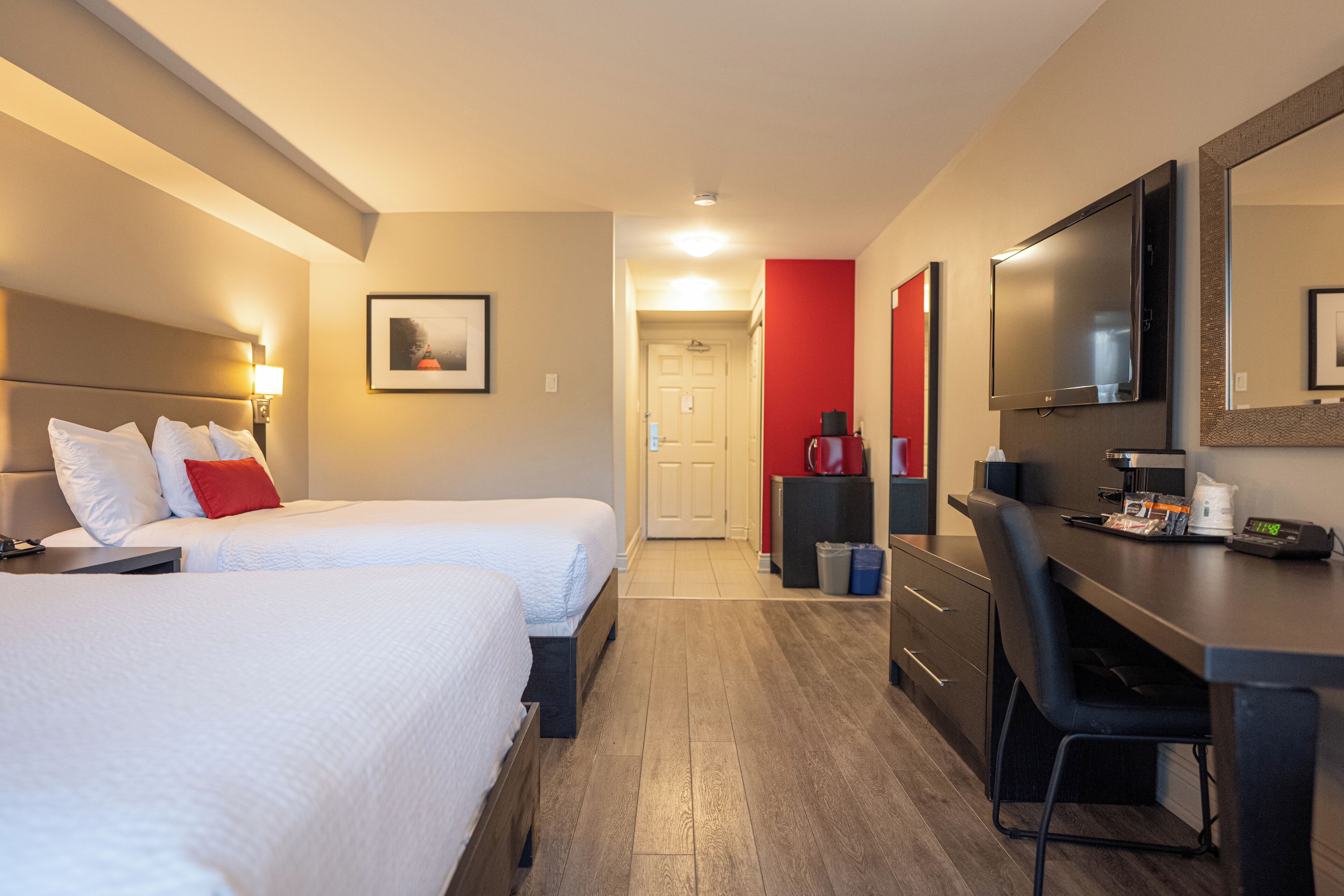 Une chambre d’hôtel avec deux lits, un bureau, une chaise, une télévision et une machine à café.