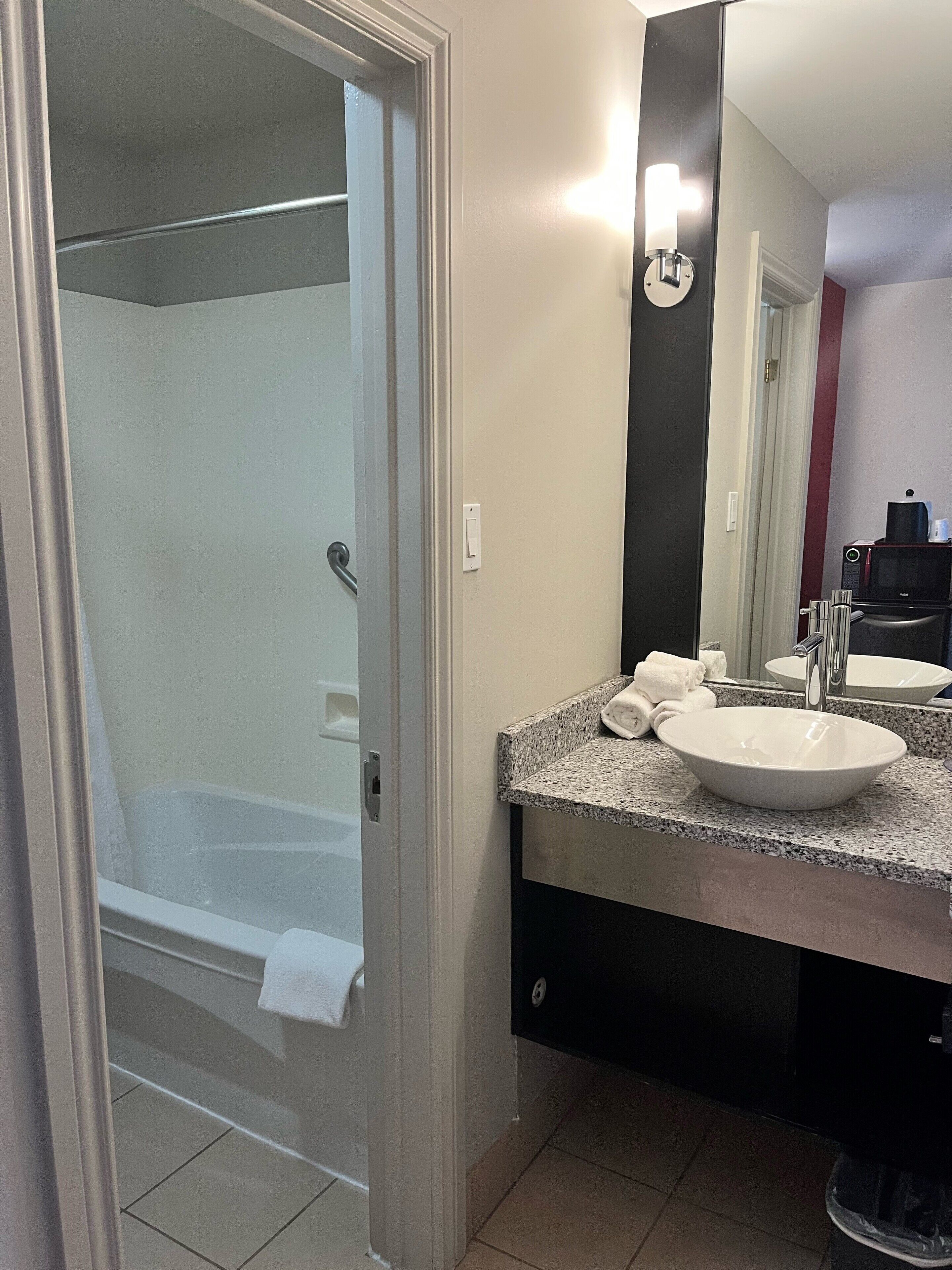 A bathroom with a bathtub, a sink, a mirror, and a towel rack.