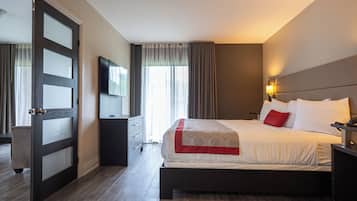 A hotel room with a large bed, a TV mounted on the wall, a bedside table, and a door with frosted glass panels.