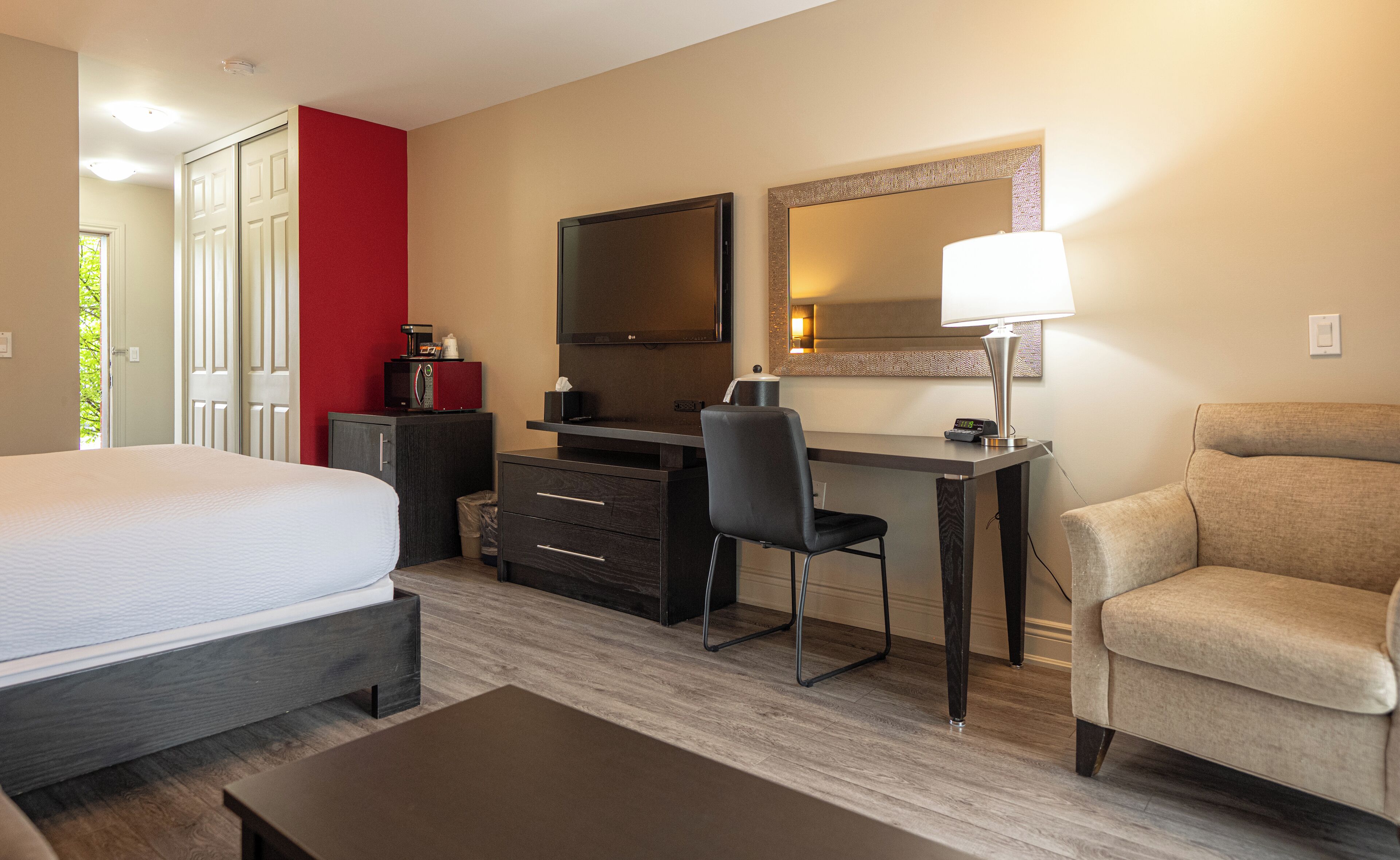 Una habitación de hotel con cama, escritorio, silla y sofá.