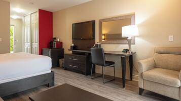 Una habitación de hotel con cama, escritorio, silla y sofá.