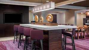 A modern bar area with a central island, bar stools, and a flat-screen TV mounted on the wall.