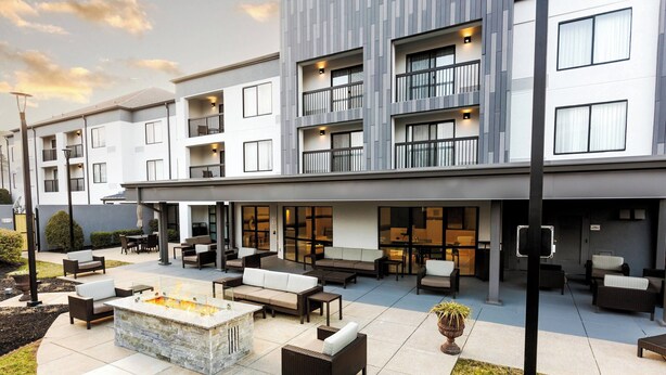 A modern building with a patio area featuring outdoor seating and a fire pit.