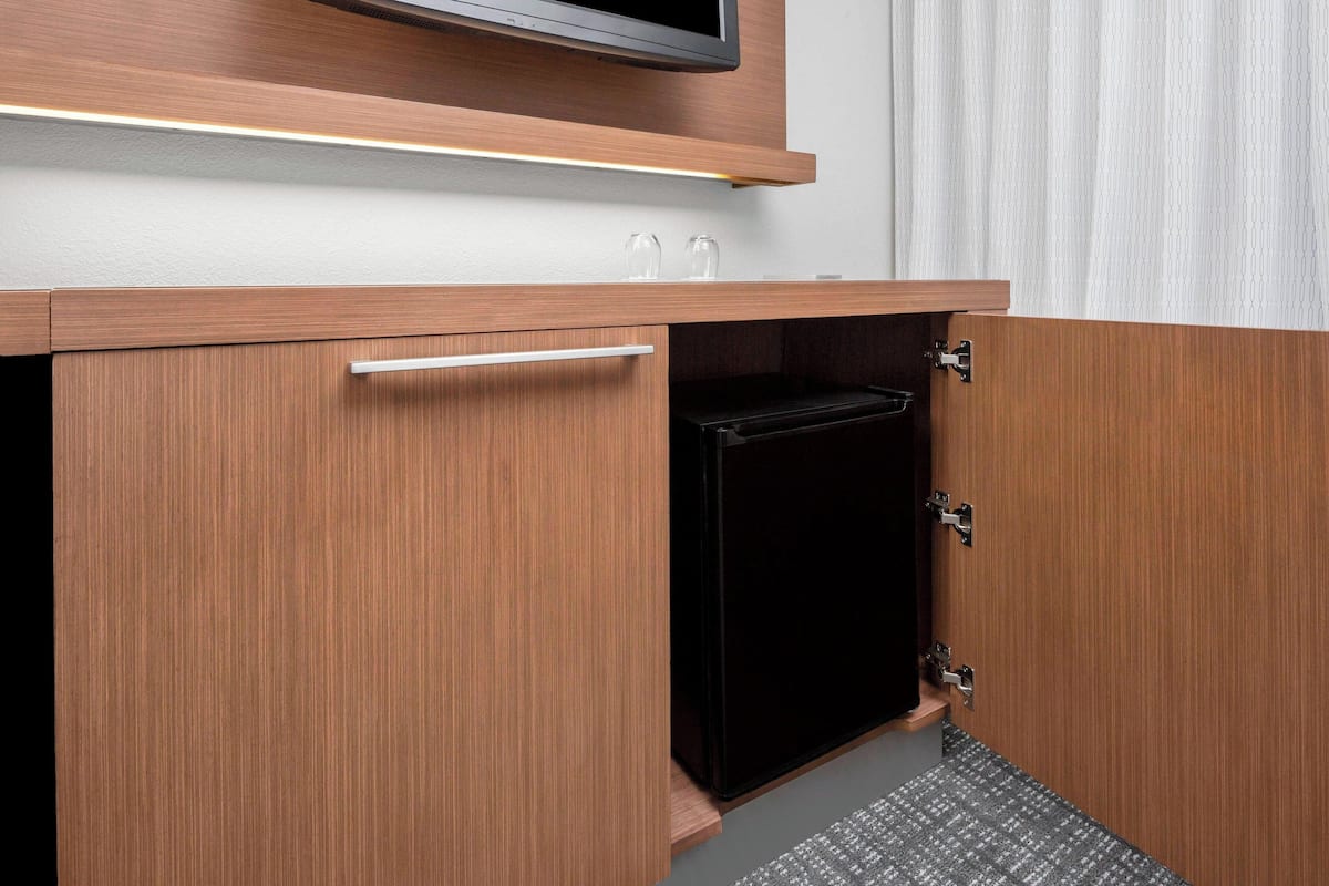 Un mueble de madera con televisor integrado, un cajón pequeño y un electrodoméstico negro.