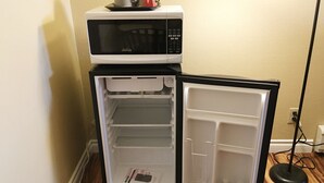 Un petit réfrigérateur doté d’un four à micro-ondes sur le dessus, avec plusieurs étagères et un compartiment congélateur.