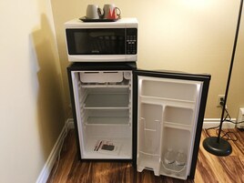 Un refrigerador compacto con un microondas encima, que cuenta con varios estantes y un compartimento congelador.