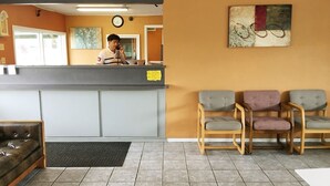 Un espace d’accueil avec un comptoir, une horloge et trois chaises.