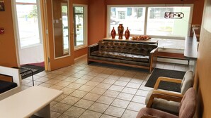 Un espace d’attente comprenant un canapé en cuir, des chaises en bois, un banc et un comptoir d’accueil.