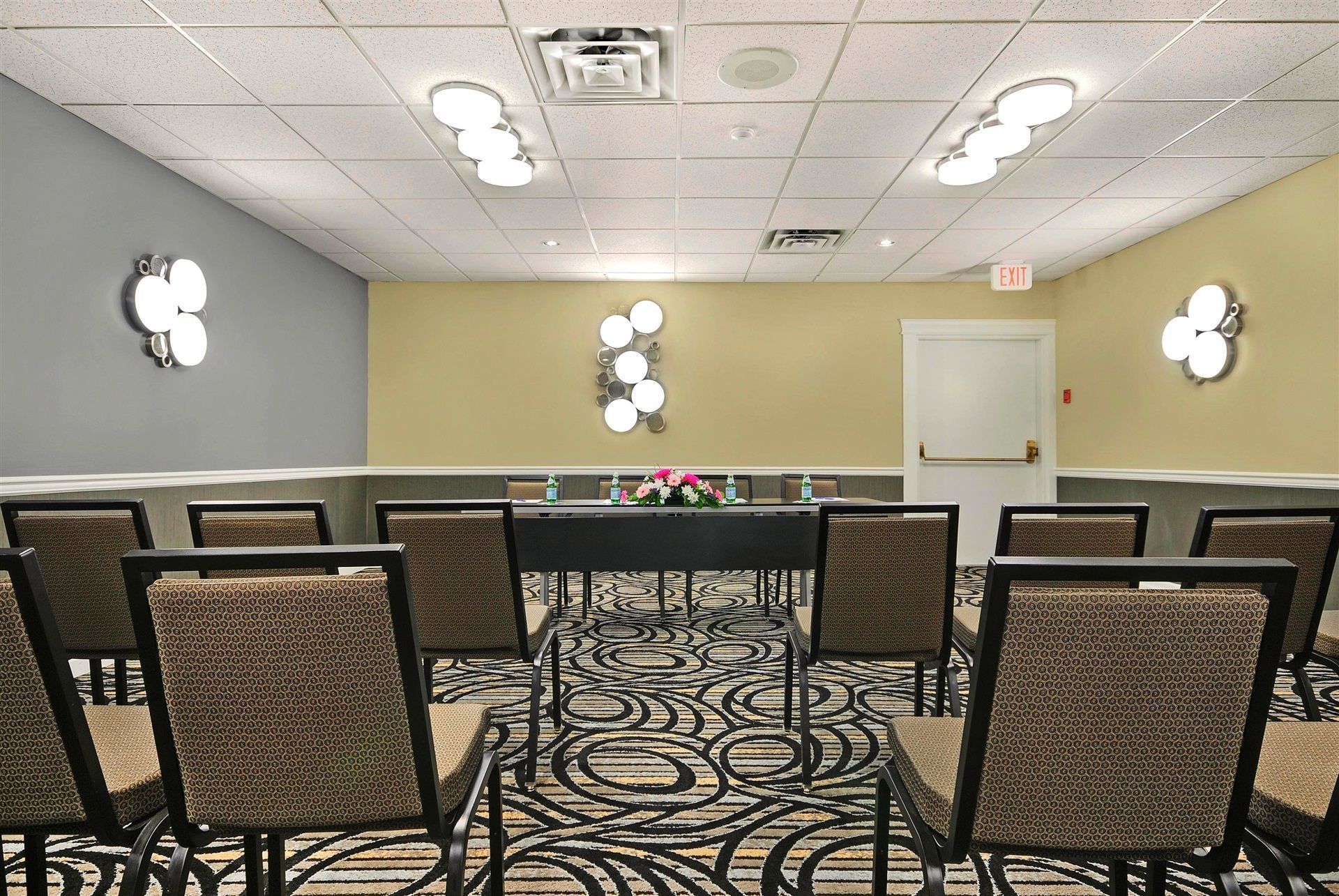 A conference room with a long table, chairs, and decorative wall sconces.