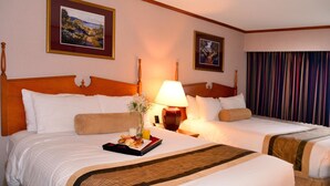 Una habitación de hotel con dos camas, una mesita de noche con lámpara y cuadros en la pared.