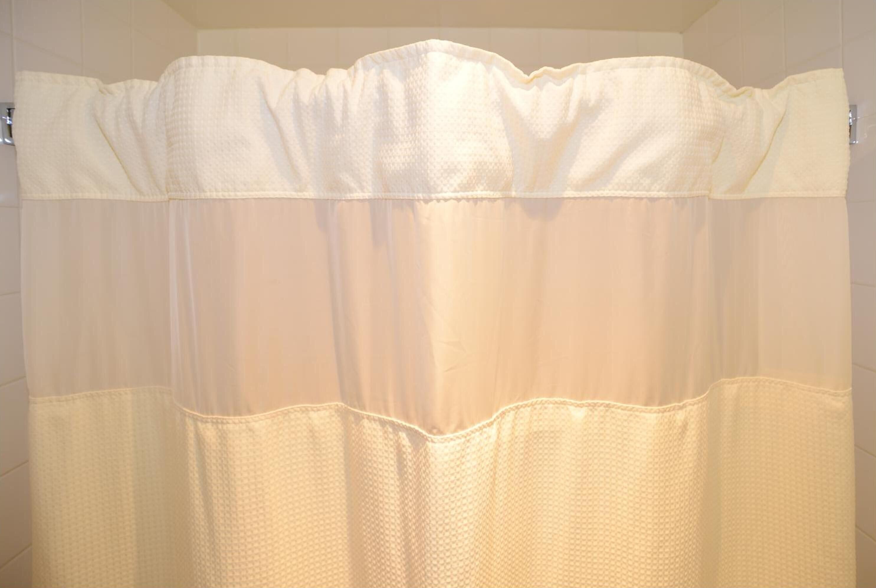 Ein Badezimmer mit weißer Duschvorhang.
