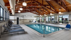 A swimming pool with lounge chairs, wooden beams, and large windows. - Courtyard by Marriott Anchorage Airport (Anchorage)