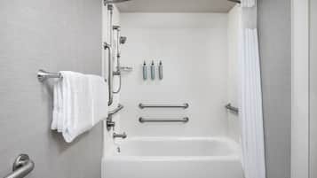 Une salle de bain moderne équipée d’une baignoire, de barres d’appui, d’un porte-serviettes et d’un rideau de douche.
