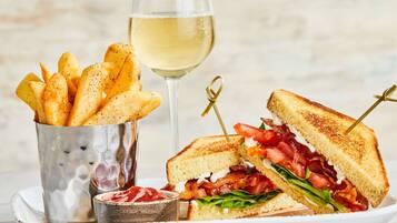 Ein Sandwich mit Pommes und einem Glas Weißwein.