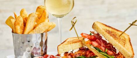A sandwich with a side of fries and a glass of white wine.