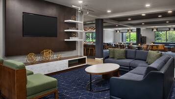 A modern lounge area with a large sofa, a coffee table, and a TV mounted on the wall.