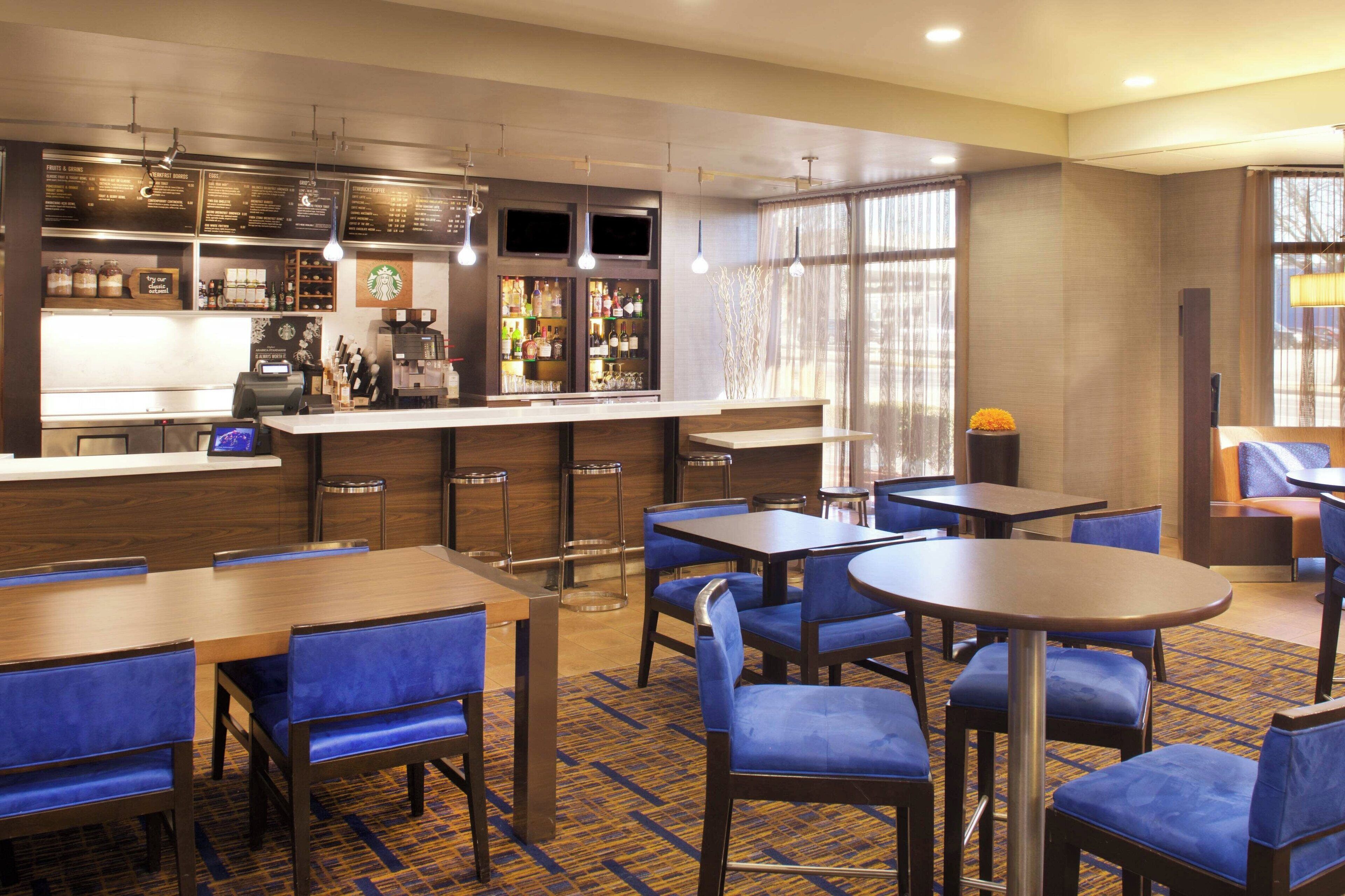 A hotel lobby with a bar area, seating arrangements, and a large window.