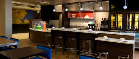 A modern bar area with a counter, stools, and a menu board.