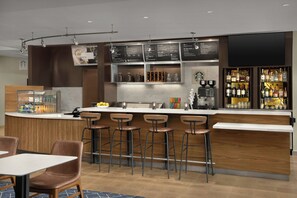 A bar area with a menu board, bar stools, a coffee machine, and a coffee press. - Courtyard by Marriott Bloomington (Bloomington)