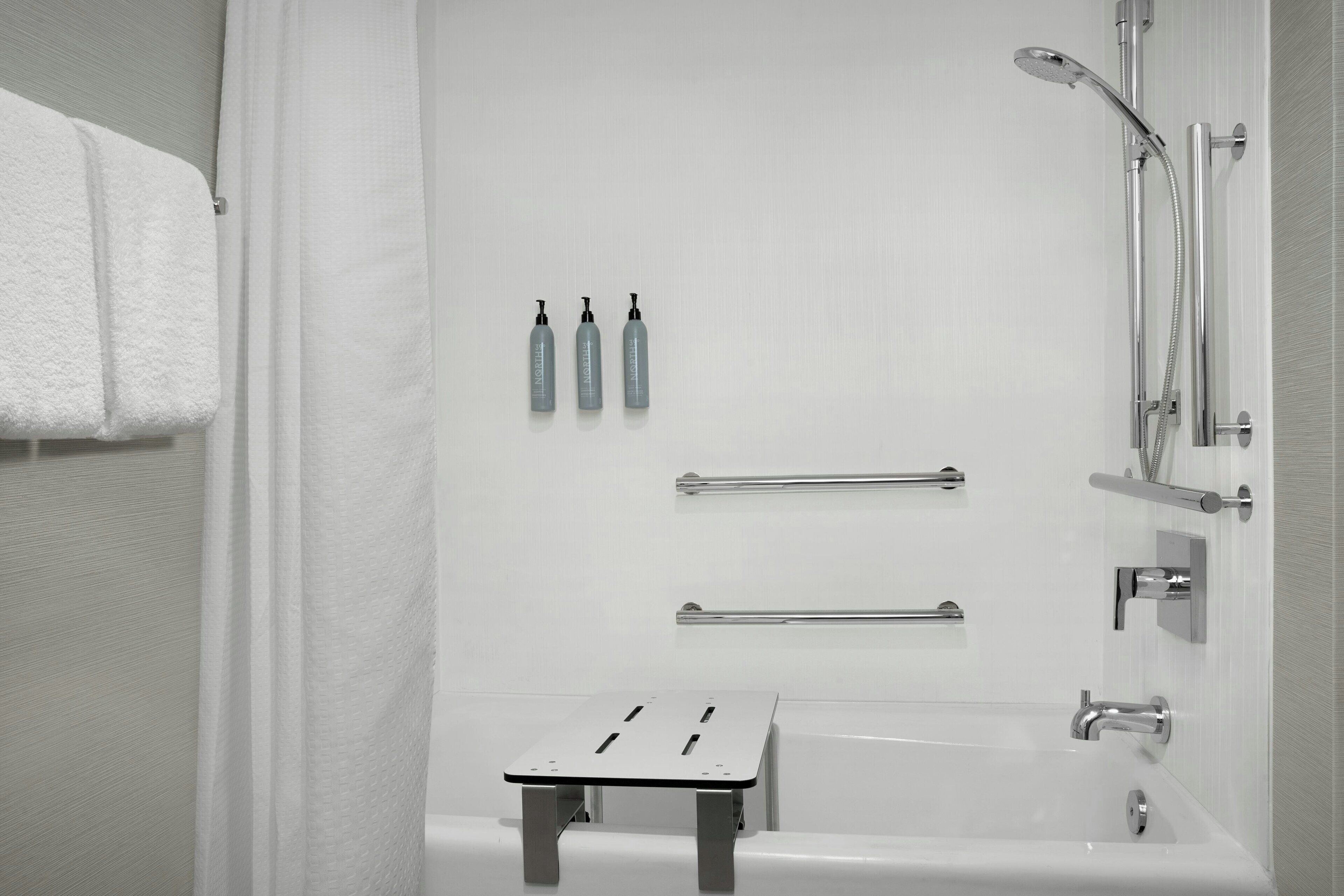 Une salle de bain moderne avec une baignoire, une douche et un petit tabouret.
