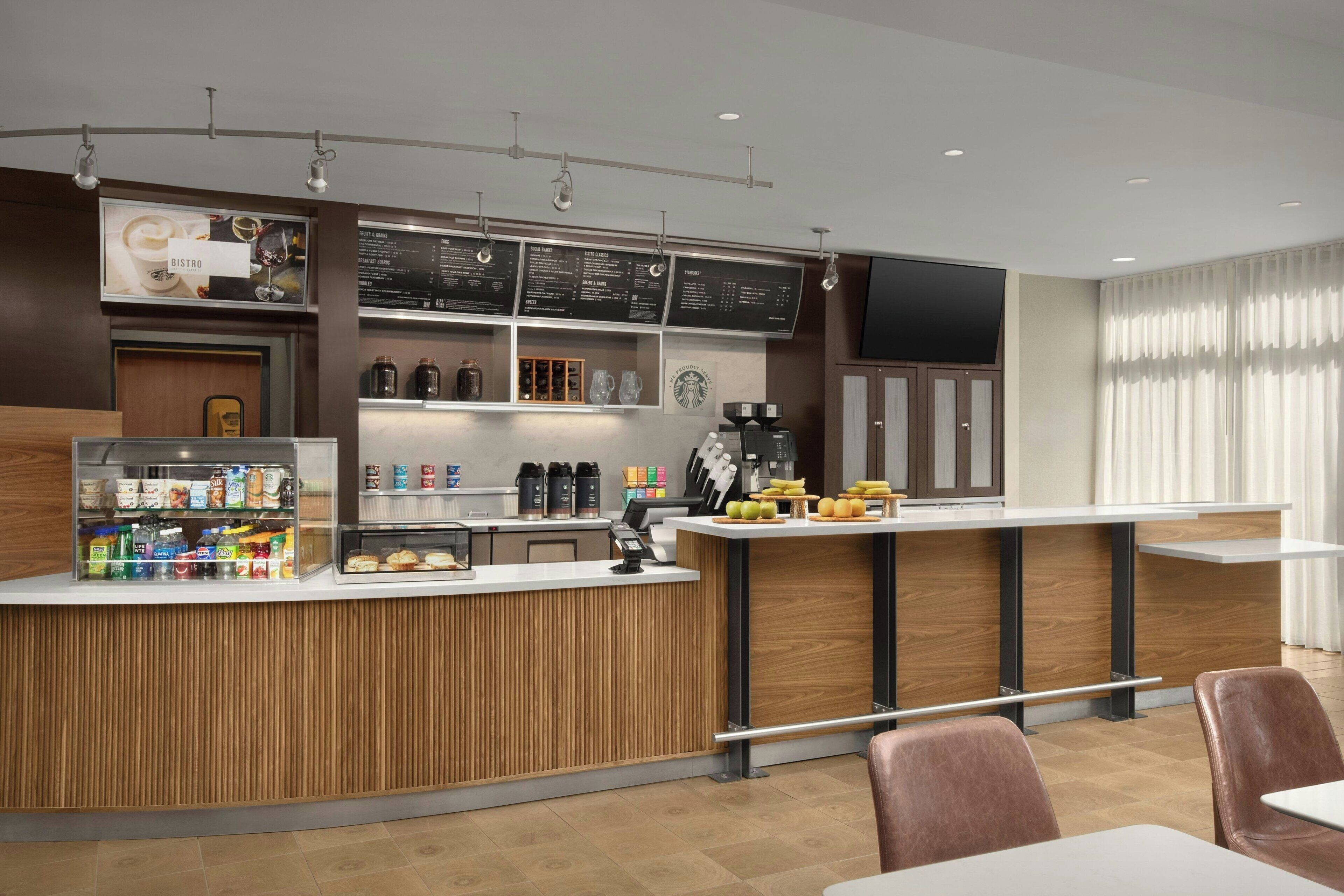 A modern cafe with a wooden counter, menu boards, and a coffee machine.