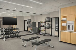 A modern gym with weightlifting equipment, exercise balls, and a bench.