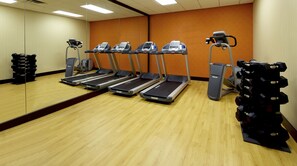 A gym with four treadmills, a weight stack, and a large mirror. - Courtyard by Marriott Bloomington (Bloomington)