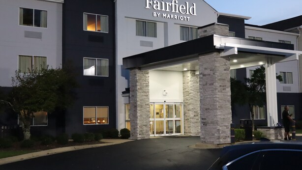 A Fairfield by Marriott hotel entrance with a stone facade, large glass doors, and a parking area in front. - Fairfield Inn Tuscaloosa by Marriott (Tuscaloosa)