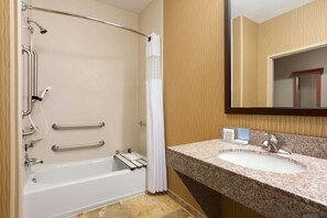 A bathroom with a bathtub, shower, grab bars, a sink, and a mirror. - Hampton Inn Wichita-East (Wichita)