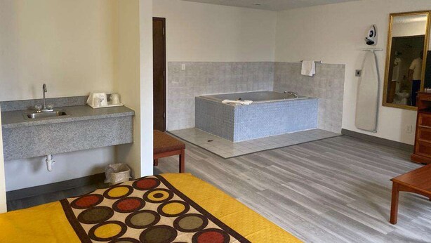 A bathroom with a bathtub, a sink, and a mirror. - Americas Best Value Inn West Frankfort (West Frankfort)