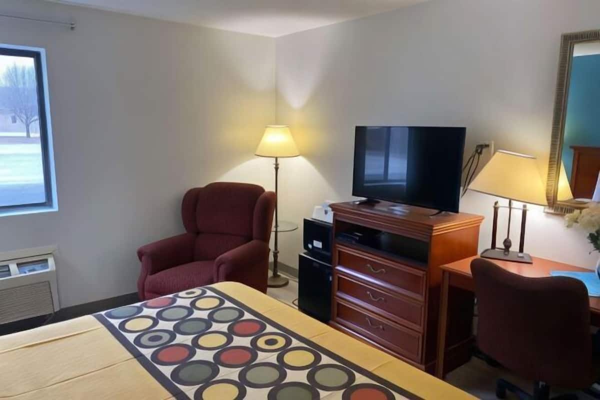 Une chambre d’hôtel avec un lit, un bureau, une chaise, une télévision et une fenêtre.
