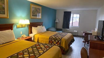 A hotel room with two beds, a desk, a chair, a desk lamp, a telephone, and a window with curtains.