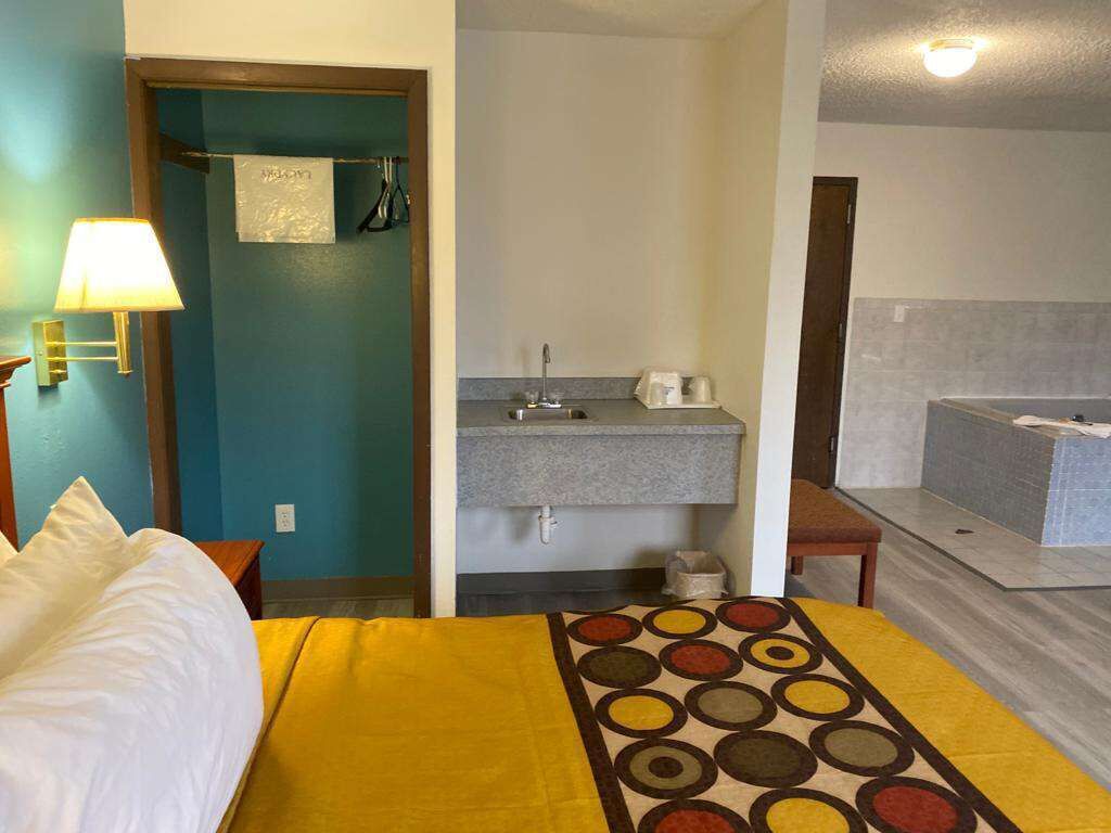 A hotel room with a bed, a bedside lamp, a bathroom with a sink and a bathtub.