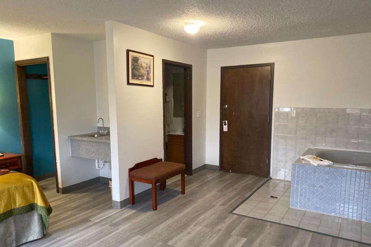 Une pièce comprenant un lit, un banc, un lavabo, une porte et une baignoire.
