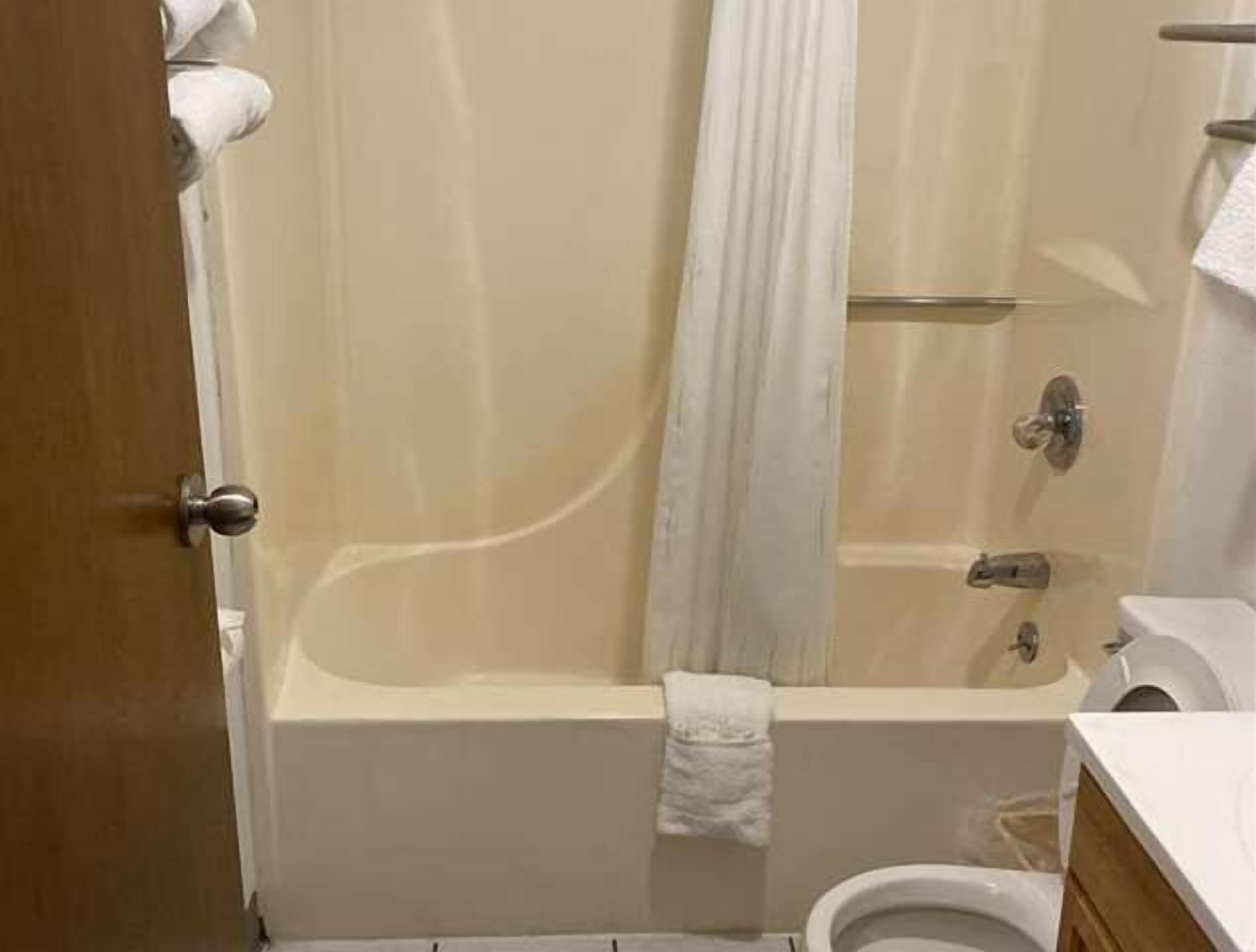A bathroom with a bathtub, toilet, and a shower curtain.