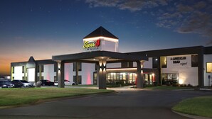 A hotel with a prominent 'Super 8' sign, a 'The American Road' sign, and a well-lit entrance. - Super 8 by Wyndham Wichita South (Wichita)