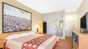 A hotel room with a large bed, a television, a desk, and a bathroom visible through an open door. - Super 8 by Wyndham Wichita South (Wichita)
