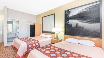 Two beds with patterned bedspreads, a framed mountain landscape, and a wardrobe with a mirror.