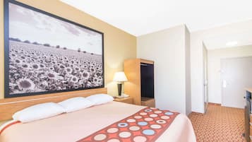 A hotel room with a large bed, a nightstand with a lamp, a wardrobe, and a door leading to another room.