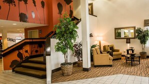 A hotel lobby with a staircase, seating area, and a large plant. - Sleep Inn Pelham Oak Mountain (Pelham)
