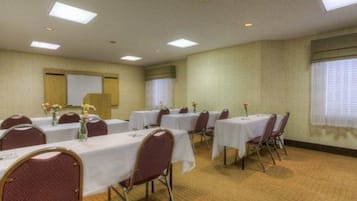 A conference room with multiple tables and chairs, a whiteboard, and a projector screen.