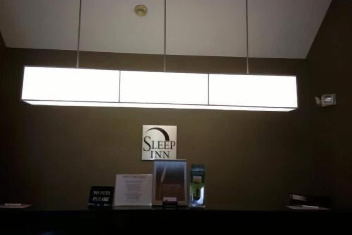 Zona de recepción con un cartel de Sleep Inn, un mostrador de recepción y un letrero que indica 'No se admiten mascotas'.