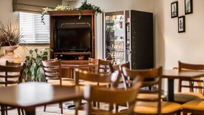 A cozy indoor seating area with wooden tables and chairs, a flat-screen TV, and a vending machine. - Sleep Inn Pelham Oak Mountain (Pelham)