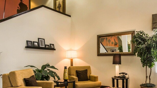 A living room with two armchairs, a coffee table, a lamp, a mirror, and a potted plant. - Sleep Inn Pelham Oak Mountain (Pelham)